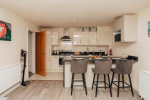 a kitchen with white cabinets and bar stools at Henley town centre with parking in Henley on Thames