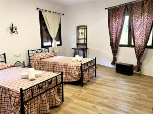 1 dormitorio con 2 camas y 2 ventanas en La Almazara Del Guijo, en Guijo de Santa Bárbara
