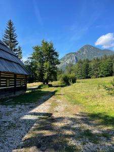 a dirt road next to a barn with mountains in the background at 200-Jahre altes Koschuta Bauernhaus 