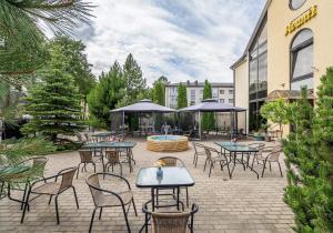 un patio con mesas y sillas frente a un hotel en Avanti apgyvendinimas-restoranas en Biržai