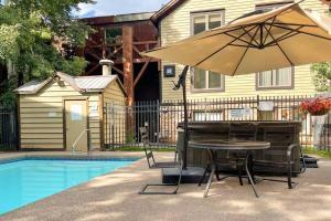 a table and an umbrella next to a pool at Premier Downtown Telluride Condo with Pool, Hot Tub & Parking in Telluride