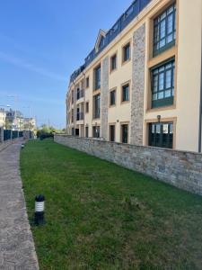 a large building with a stone wall next to a grass field at Las Catedrales ático Oceano VI in Barreiros