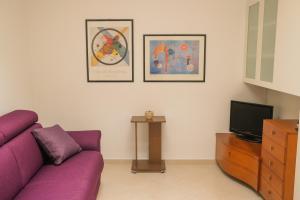 a living room with a purple couch and a tv at Suite Sabean by STHEY in Monopoli