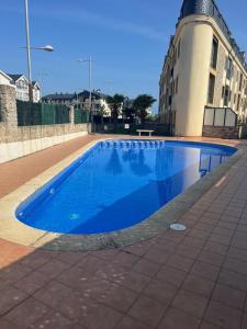 a blue swimming pool in front of a building at Las Catedrales ático Oceano VI in Barreiros