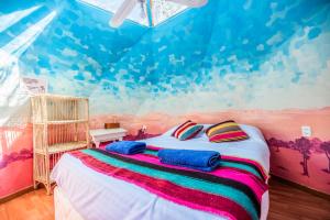 a bedroom with a bed with a painting on the wall at Casa Voyage Hostel in San Pedro de Atacama