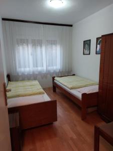 two beds in a room with wooden floors at Guest House Planinic in Čitluk