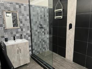 a bathroom with a shower with a sink and a mirror at 12 Calderbank in Potchefstroom