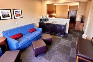 a living room with a blue couch and a kitchen at Baymont by Wyndham Phoenix North in Phoenix