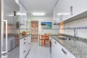 biała kuchnia ze zlewem i stołem w obiekcie Sandy Beach w Maladze