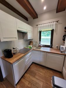 a kitchen with white cabinets and a sink and a window at Domek w Bieszczadach in Lutowiska