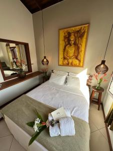 a bedroom with a large white bed with a statue at Residencial Villa Cris in Bertioga