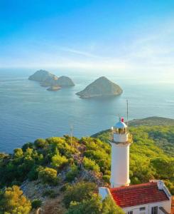 un faro sentado en la cima de una colina junto al océano en İzol Apart Evleri Adrasan, en Kumluca