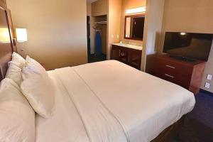 a bedroom with a large white bed and a television at Baymont by Wyndham Phoenix North in Phoenix