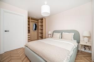 a white bedroom with a large bed and a closet at Apartments 7vakarai with free parking in Vilnius