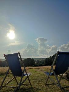 dos sillas sentadas en un campo con el sol en el cielo en Porthleven Glamping, en Porthleven