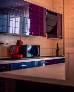 a kitchen with purple cabinets and a red appliance at MOZART RESIDENCE PLOIEȘTI Family and Business Apartment in Ploieşti