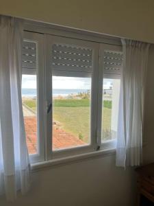 two windows with white curtains and a view of the ocean at Mojomar Pinamar Hotel in Pinamar