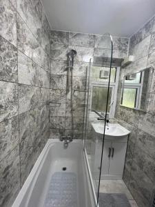 a bathroom with a bath tub and a sink at T Lodge in Abbey Wood