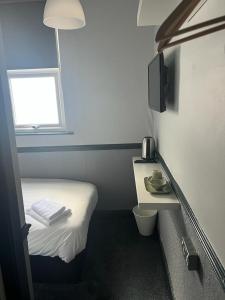 ein kleines Zimmer mit einem kleinen Bett und einem Fenster in der Unterkunft Letting Rooms @ Charles Dickens in Wigan