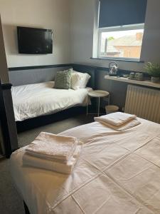 a bedroom with two beds and a tv on the wall at Letting Rooms @ Charles Dickens in Wigan