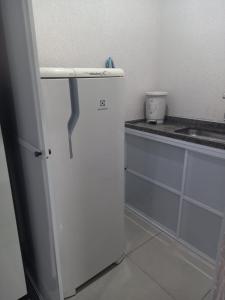 um frigorífico branco numa cozinha ao lado de um balcão em FLAT 2 - CENTRO DE ITAPIRA em Itapira