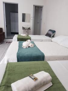 a group of four beds in a room with towels at FLAT 2 - CENTRO DE ITAPIRA in Itapira