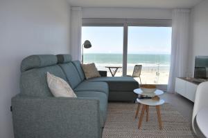 a living room with a couch and a view of the beach at Studio Zeezicht by Qua-Lyne in Ostend