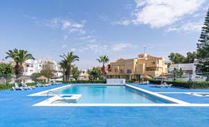 una piscina con sillas y edificios en el fondo en Apartamento luminoso cerca al mar, en Roquetas de Mar