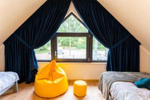 um quarto com uma grande janela e uma cadeira amarela em Domki Górkło em Górkło