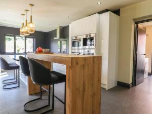 a kitchen with a large wooden island with bar chairs at Beautiful home with hot tub near Cambridge in Royston
