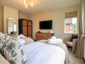 a hotel room with two beds and a television at Beautiful home with hot tub near Cambridge in Royston