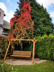 a wooden swing in front of a tree with red flowers at D.W. JULIA in Władysławowo