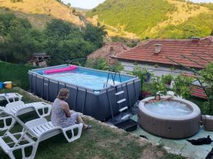 a woman sitting on a chair next to a hot tub at Vila Mir in Pirot