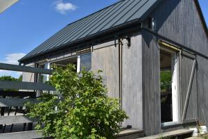 a wooden house with a black roof at Domek na Winnicy Zagrabie in Rybna