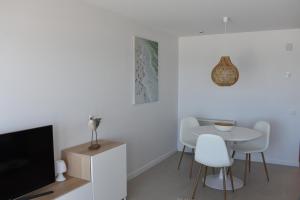 a living room with a tv and a table and chairs at Studio Zeezicht by Qua-Lyne in Ostend