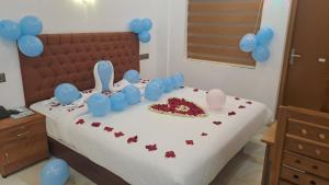 una cama con un pastel y globos en ella en MARINA SUITES AIRPORT HOTEL, en Kochi