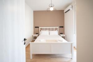 ein weißes Schlafzimmer mit einem weißen Bett und einem Fenster in der Unterkunft Feelin' Good Apartment in Ioannina