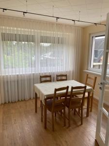 een eetkamer met een tafel, stoelen en ramen bij FeWo Ibis in Bottrop