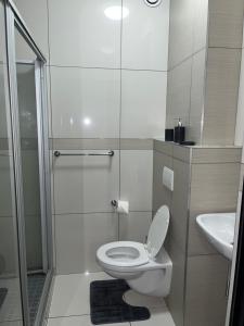 een witte badkamer met een toilet en een douche bij The Den in Windhoek