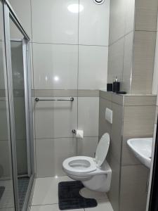 a white bathroom with a toilet and a shower at The Den Marensky Towers in Windhoek