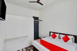 OYO Flagship Amazing Inn في Murādnagar: غرفة نوم بسرير ومخدات حمراء