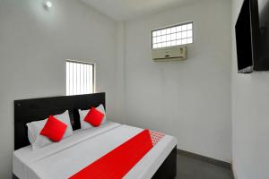OYO Flagship Amazing Inn في Murādnagar: غرفة نوم بسرير ومخدات حمراء وبيضاء