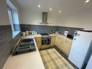 a kitchen with wooden cabinets and a white refrigerator at 4 bed house, fully equipped & close to amenities. in Hull