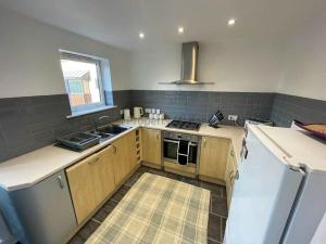 a kitchen with wooden cabinets and a sink and a refrigerator at 4 bed house, fully equipped & close to amenities. in Hull