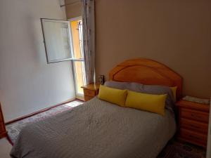 Un dormitorio con una cama con almohadas amarillas y una ventana en Appartement Agadir Salam, en Agadir