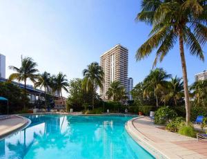 a swimming pool with palm trees and a tall building at Sunny Isles Miami HOLIDAY apartment in Miami Beach