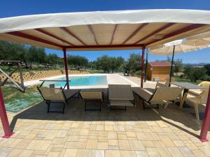 un pabellón con mesa, sillas y piscina en Agriturismo privato "La Casa Del Sole", en Castiglione del Lago