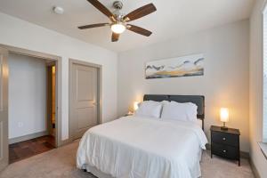 1 dormitorio con cama blanca y ventilador de techo en Comfy Retreat Balcony Views Amenities en Woodbridge