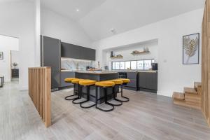 a kitchen with yellow stools around a black counter at Luxury Riverside Retreat in Broughton