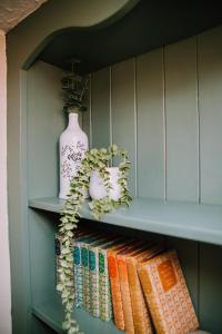 un estante de libros con libros y un jarrón. en Pebbles Cottage, en Caister-on-Sea